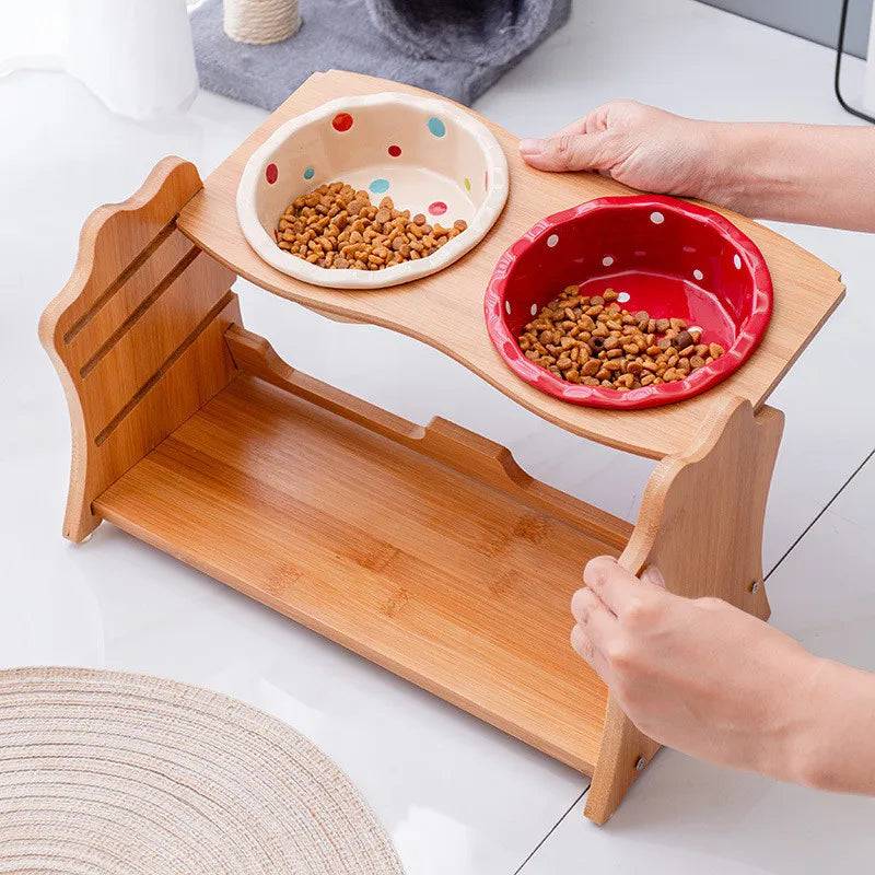 Pawciara raised ceramic double bowl stand for dogs and cats, with white ceramic bowls on a wooden table for food and water.