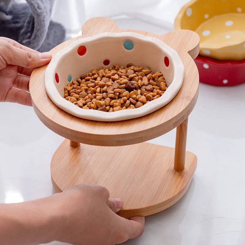 White raised ceramic double bowl stand for dogs and cats on wooden table, food and water dishes for pets.